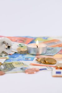 a lighted candle on top of a paper money