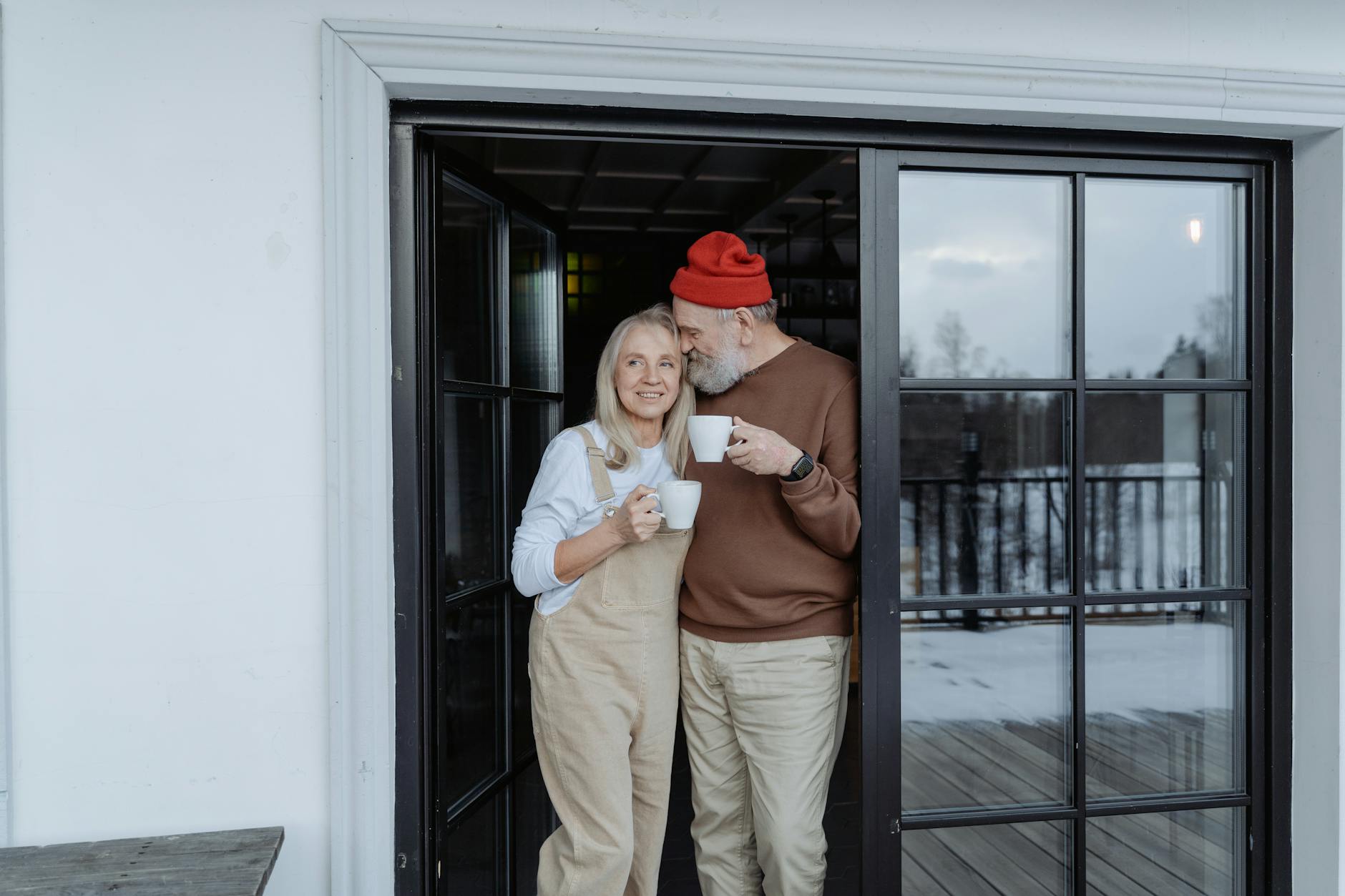 man and woman standing by the door holding mugs